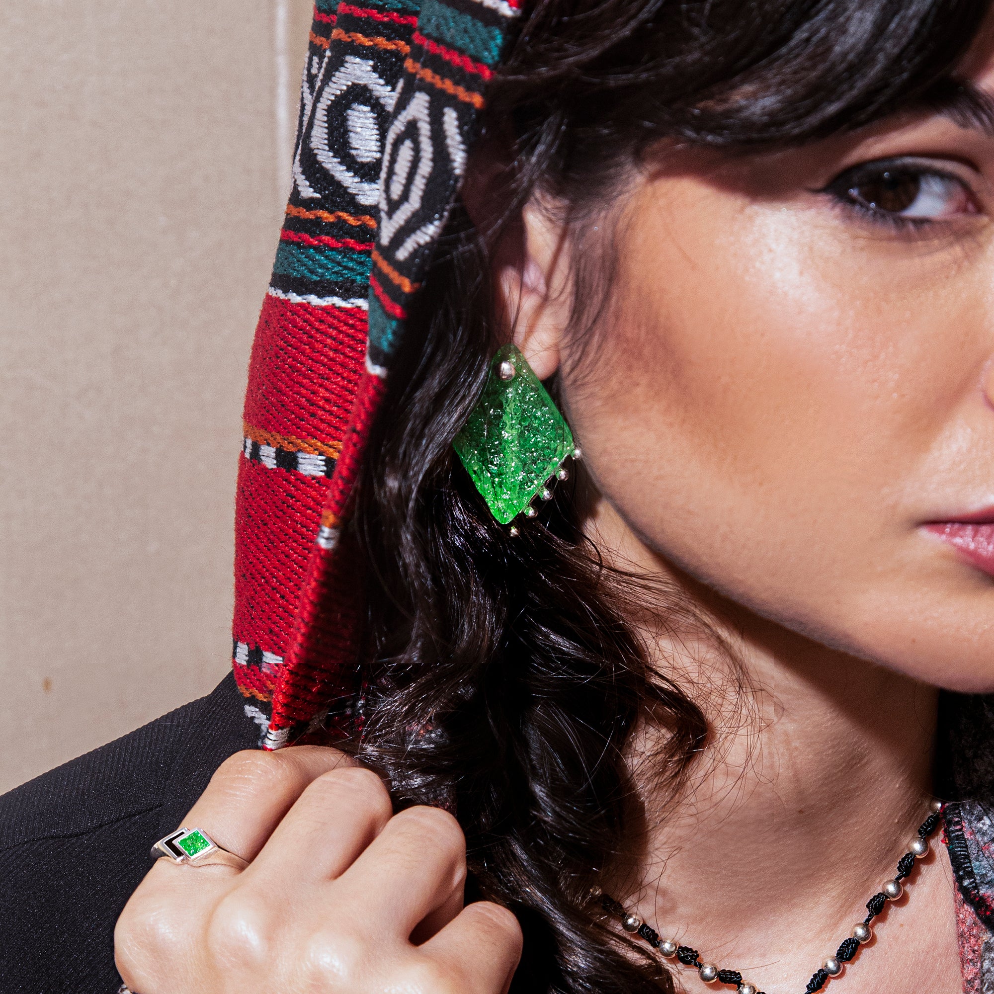 A model wearing Sterling Silver Earrings with crushed green jade stones crafted into a rhombus-shaped stone that is interchangeable. 